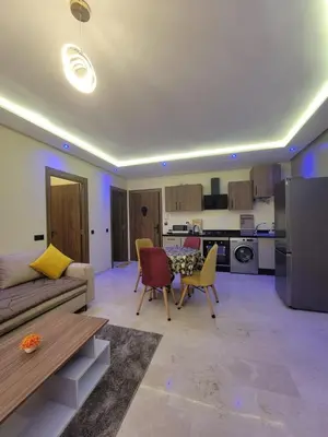 a living room with a couch and chairs and a kitchen at Élégante Appartement au centre de Marrakech , Piscine - Parking gratuit in Marrakech