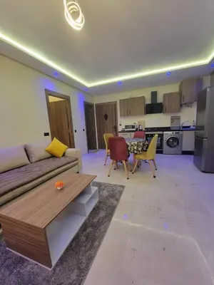 a living room with a couch and chairs and a kitchen at Élégante Appartement au centre de Marrakech , Piscine - Parking gratuit in Marrakech