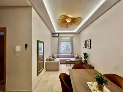 a living room with a ceiling fan and a table at Appartement cosy et moderne familial in Marrakech
