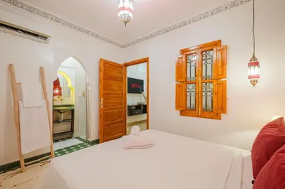 a bedroom with a white bed and a kitchen at Riad Dar Z'r in Marrakech