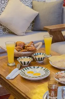 a table topped with plates of food and orange juice at Riad Dar Z'r in Marrakech
