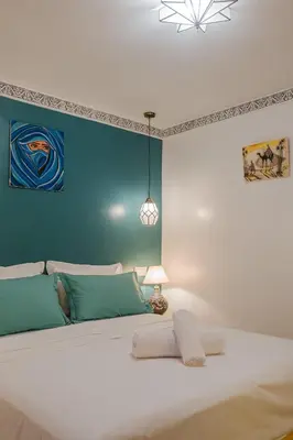 a bedroom with a large white bed with a blue wall at Riad Dar Z'r in Marrakech