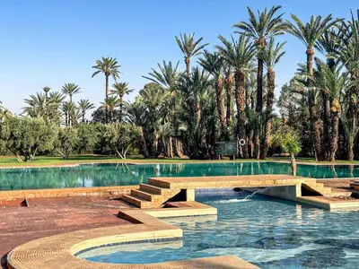 a swimming pool with a bridge and palm trees at Palmeraie Tradition and Modernity in Marrakech