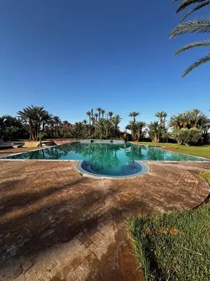 a swimming pool in a park with palm trees at Palmeraie Tradition and Modernity in Marrakech