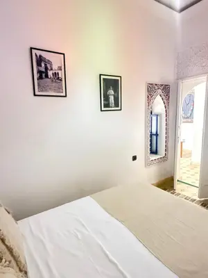 a white bedroom with a bed and two pictures on the wall at Riad Marocain avec jacuzzi sur la terrasse entièrement louer avec 3 chambres pour 6 personnes dans la médina proche de la place Jemma el fna in Marrakech
