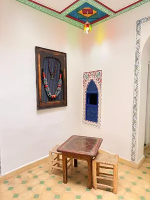 a room with a table and a picture on the wall at Riad Marocain avec jacuzzi sur la terrasse entièrement louer avec 3 chambres pour 6 personnes dans la médina proche de la place Jemma el fna in Marrakech