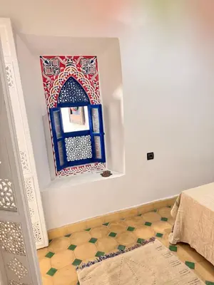 a room with a moroccan window and a rug at Riad Marocain avec jacuzzi sur la terrasse entièrement louer avec 3 chambres pour 6 personnes dans la médina proche de la place Jemma el fna in Marrakech
