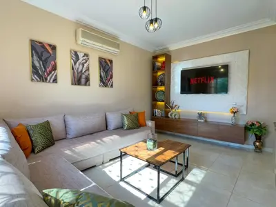 a living room with a couch and a tv at Appartement lumineux avec Jardin à la palmeraie in Marrakech