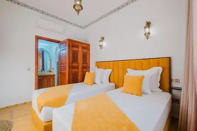 two beds in a room with white and orange pillows at Riad Marrakech Dar Tivawin 3 rooms With Pool Private Riad in Marrakech