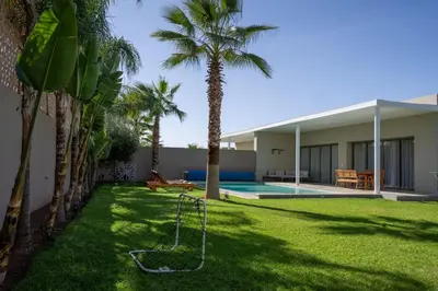 a yard with palm trees and a swing at Villa Seyana 1 Zero Vis a Vis et Piscine Chauffee in Marrakech