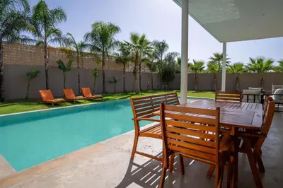 a wooden table and chairs next to a swimming pool at Villa Seyana 2 Zero vis a vis, Piscine Chauffee in Marrakech