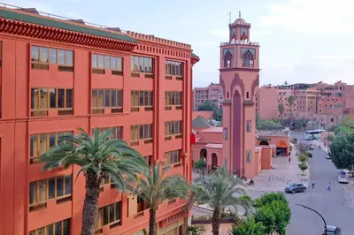 a city with a clock tower and a street with palm trees at DannaMs Apartment MohamedV Hivernage in Marrakech