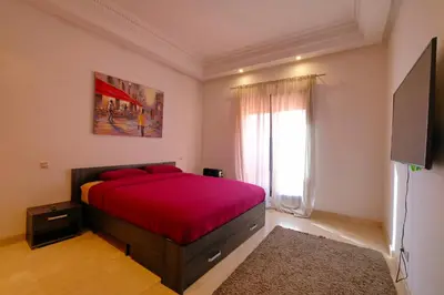 a bedroom with a bed with red sheets and a window at DannaMs Apartment MohamedV Hivernage in Marrakech