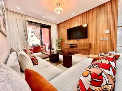 a living room with a couch and a tv at Modern and Central Apartment with Terrace and Free Parking in Marrakech