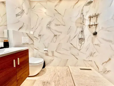 a bathroom with a toilet and a marble wall at Modern and Central Apartment with Terrace and Free Parking in Marrakech