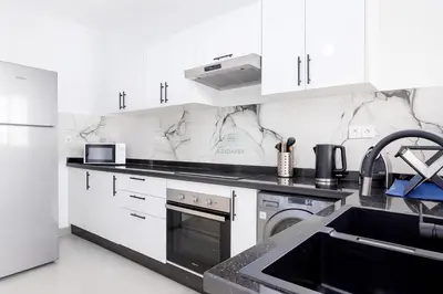 a white kitchen with a stove and a sink at Kridarek - Appartement Élégant à Marrakech in Marrakech