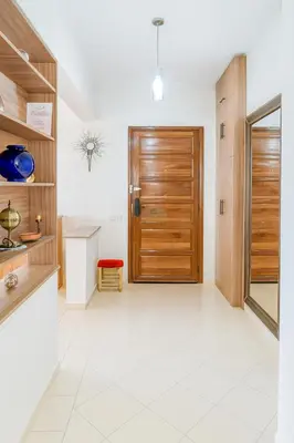 a hallway with a wooden door and a white tile floor at Kridarek - Appartement Élégant à Marrakech in Marrakech