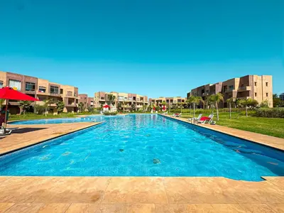 a large blue swimming pool with buildings in the background at elegance apartment in Marrakech in Marrakech