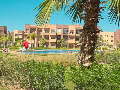 a palm tree in front of a building with a pool at elegance apartment in Marrakech in Marrakech