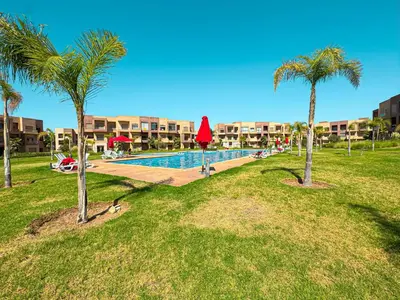 a resort swimming pool with palm trees in a park at elegance apartment in Marrakech in Marrakech
