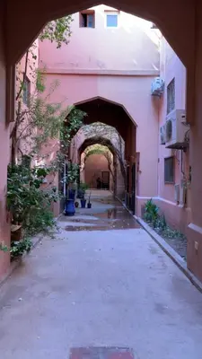 an alley with an archway in a pink building at Riad Nahara in Marrakech