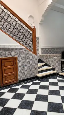 a room with a checkered floor and stairs at Riad Nahara in Marrakech