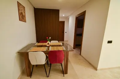a dining room table with two red chairs and a table at Superbe T3 neuf - Proche centre - Piscines et Clim - Marrakeck in Marrakech
