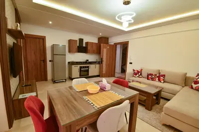 a kitchen and living room with a table and a couch at Superbe T2 neuf - Proche centre - Piscines et Balcon - Marrakech in Marrakech