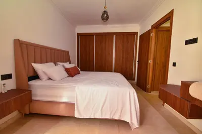 a bedroom with a bed with white sheets and pillows at Superbe T2 neuf - Proche centre - Piscines et Balcon - Marrakech in Marrakech