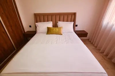 a white bed with a yellow pillow on it at Superbe T2 neuf - Proche centre - Piscines et Balcon - Marrakech in Marrakech