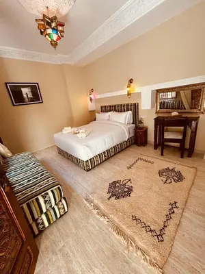 a bedroom with a bed and a desk in it at Riad LALA ASMAA Riad privé in Marrakech