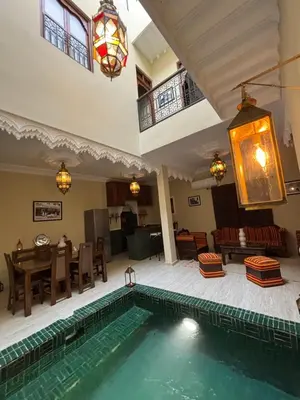 a swimming pool in a room with a table and a dining room at Riad LALA ASMAA Riad privé in Marrakech