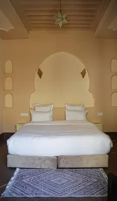 a bedroom with a large white bed with a star on the wall at Palais Andara Riad And SPA in Marrakech