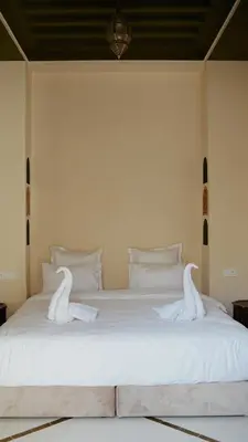 two swans sitting on top of a white bed at Palais Andara Riad And SPA in Marrakech