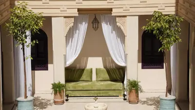 a porch with a green couch and two potted plants at Palais Andara Riad And SPA in Marrakech