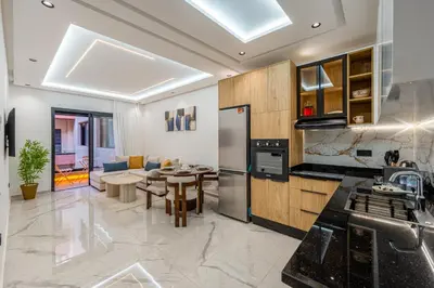 a kitchen and living room with a table and a couch at Modern Hivernage Studio Retreat Pool & central access in Marrakech