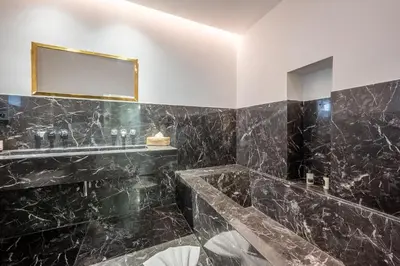 a bathroom with black marble walls and a mirror at Riad LILIA in Marrakech