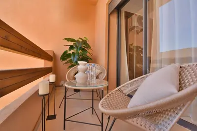 a balcony with wicker chairs and a table with a plant at Appartement Gueliz Haut de gamme Residence 5 piscines in Marrakech