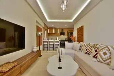 a living room with a white couch and a kitchen at Appartement Gueliz Haut de gamme Residence 5 piscines in Marrakech