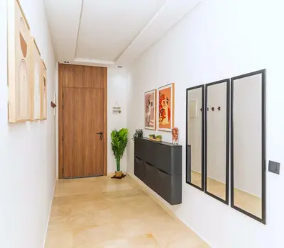 a hallway with white walls and a wooden door at Menara Garden Cosy Appartement Hivernage Marrakech in Marrakech