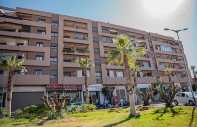 a large building with palm trees in front of it at Menara Garden Cosy Appartement Hivernage Marrakech in Marrakech