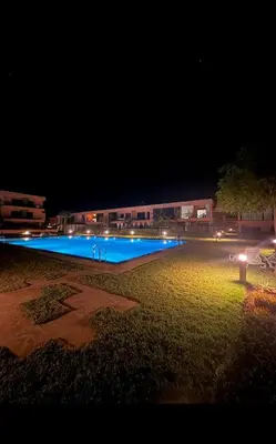 a large swimming pool at night with lights at Appartement au Domaine de Noria - Terrasse & Piscine in Marrakech