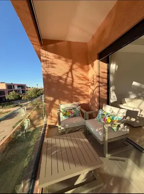 a room with a balcony with a couch and a window at Appartement au Domaine de Noria - Terrasse & Piscine in Marrakech