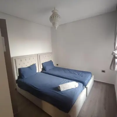 a bedroom with two beds with blue sheets and a chandelier at T3 Jade Prestigia Pool in Marrakech