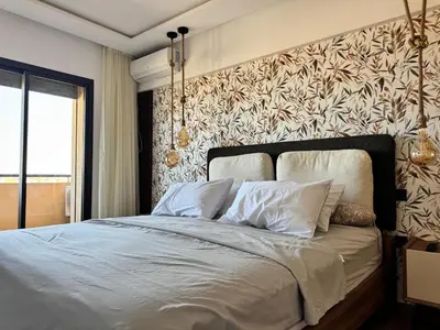 a bedroom with a large bed with a wall at Magnifique appartement avec piscine in Marrakech