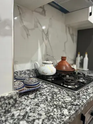 a kitchen counter with a stove with plates and a tea pot at Magnifique appartement avec piscine in Marrakech