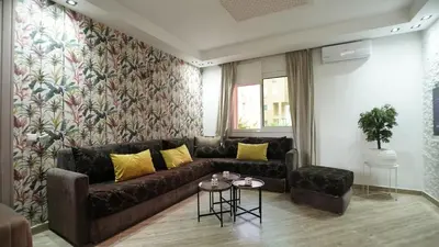 a living room with a brown couch and yellow pillows at Stylish apartment with pool access heart of Marrakech gueliz in Marrakech