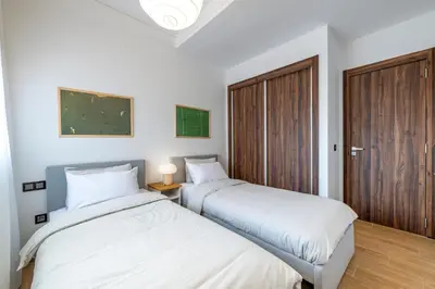 two beds in a room with white walls at Modern Apt with Balcony & Pool in Central Marrakesh in Marrakech
