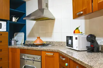 a kitchen with a stove and a microwave at Appartement HIVERNAGE deLUXE en face consulat de france et M avenu CR7 in Marrakech