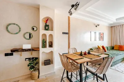 a living room with a table and chairs and a couch at Calme & moderne - Piscine - Balcon - 2 SDB in Marrakech